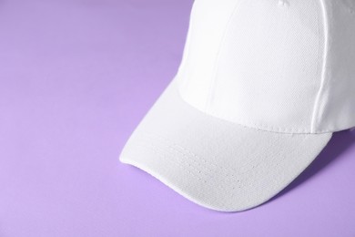 Photo of White baseball hat on violet background, closeup. Space for text
