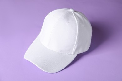Photo of White baseball hat on violet background, above view. Mockup for design