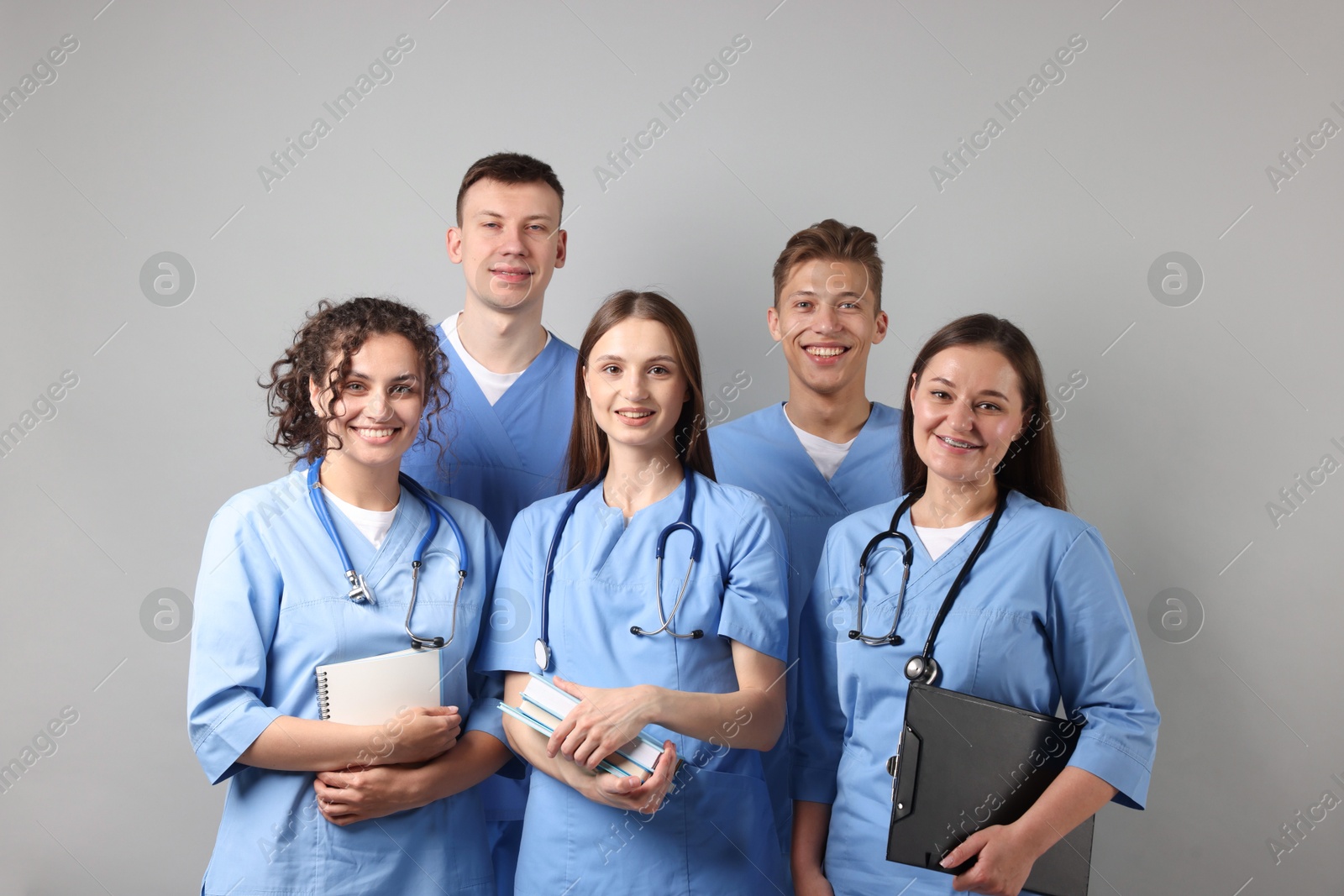 Group of medical students with books on light grey background Photo of Group of medical students with books on light grey background