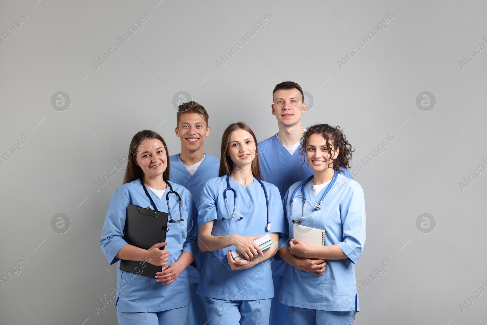 Group of medical students with books on light grey background Photo of Group of medical students with books on light grey background