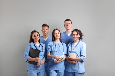 Photo of Group of medical students with books on light grey background
