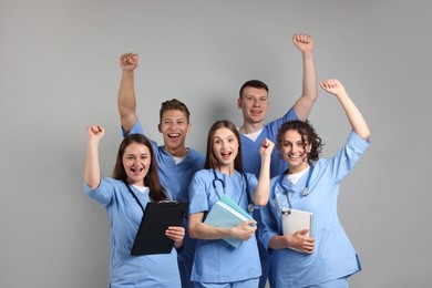 Photo of Group of excited medical students with books on light grey background