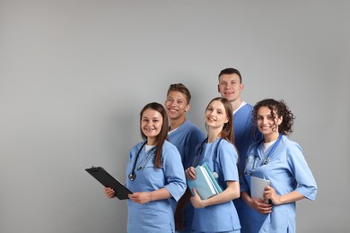 Photo of Group of medical students with books on light grey background. Space for text