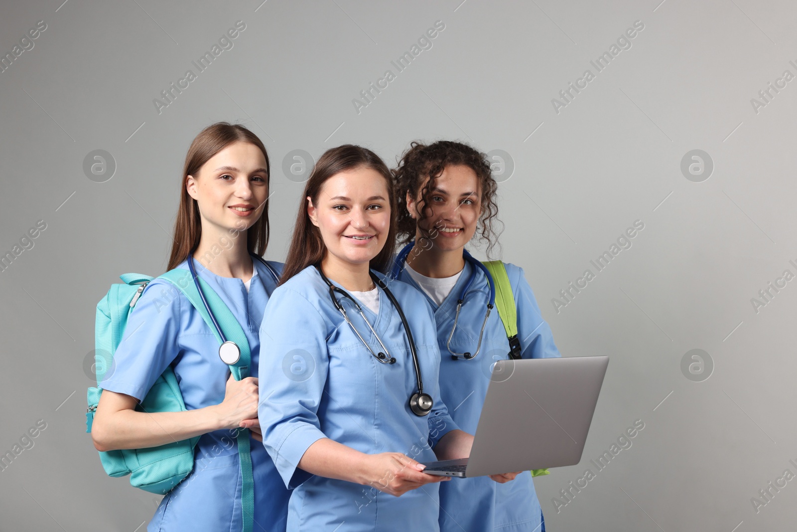 Group of medical students with laptop on light grey background Photo of Group of medical students with laptop on light grey background