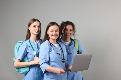 Photo of Group of medical students with laptop on light grey background