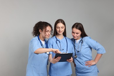 Photo of Group of medical students with clipboard on light grey background