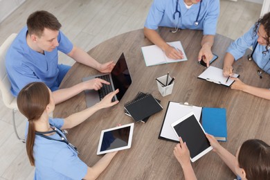 Photo of Medical students in uniforms studying together at table indoors, above view