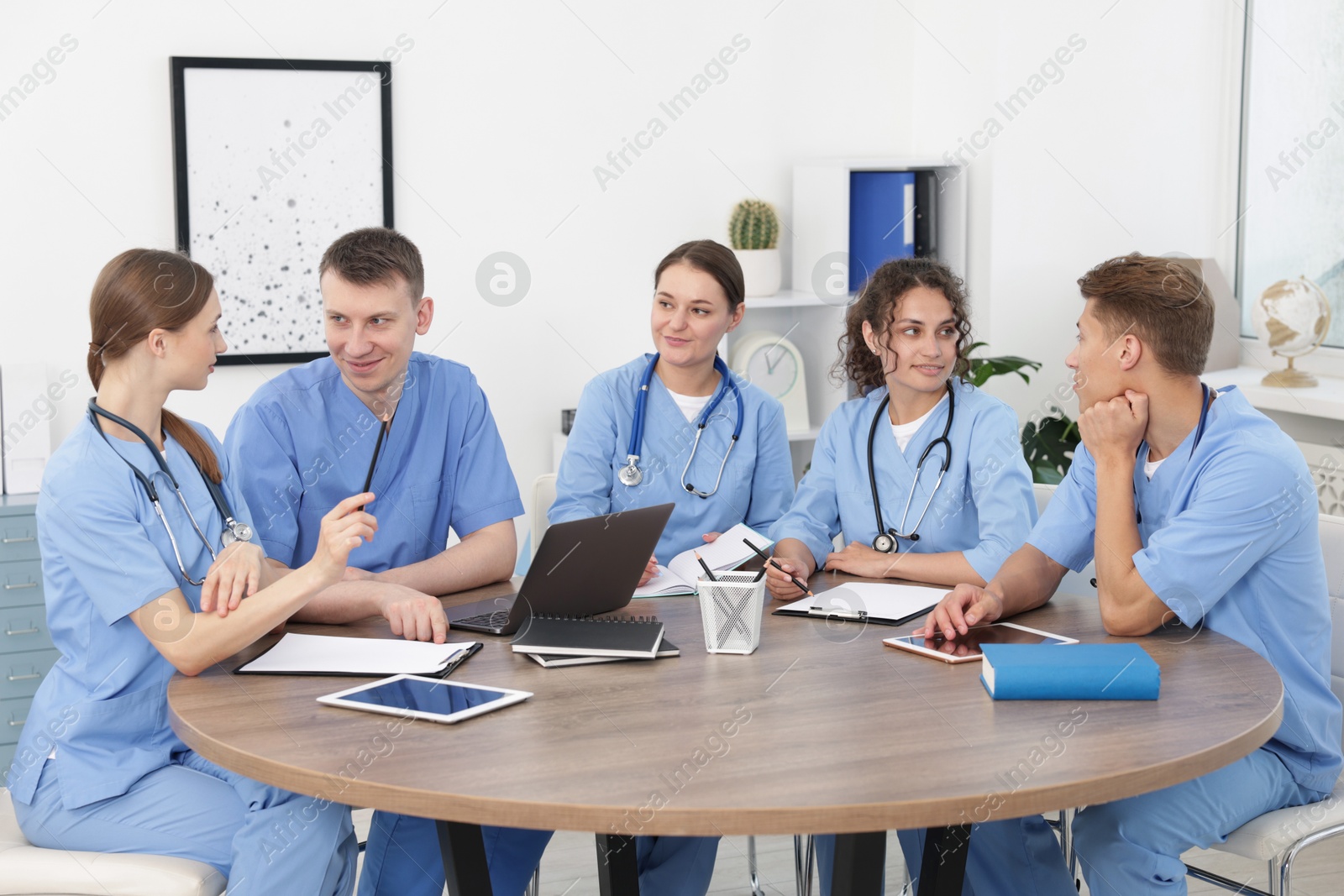 Medical students in uniforms studying together at table indoors Photo of Medical students in uniforms studying together at table indoors