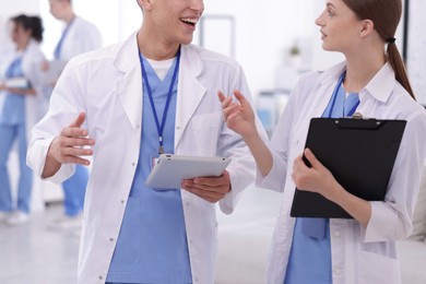 Photo of Medical students in uniforms with tablet and clipboard indoors, selective focus
