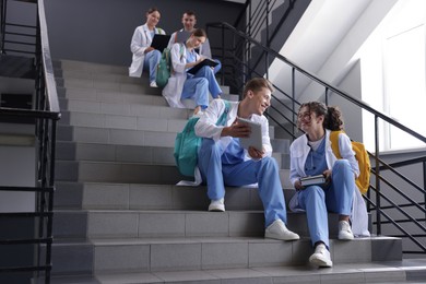 Photo of Group of medical students in uniforms on stairs indoors, low angle view