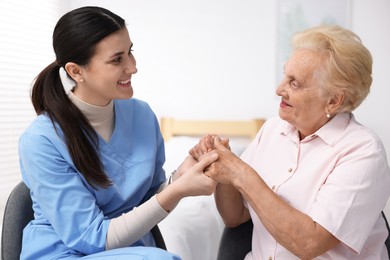 Photo of Nurse assisting senior woman indoors. Home health care service