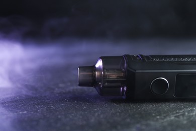 Photo of Modern electronic smoking device on black table, closeup. Space for text