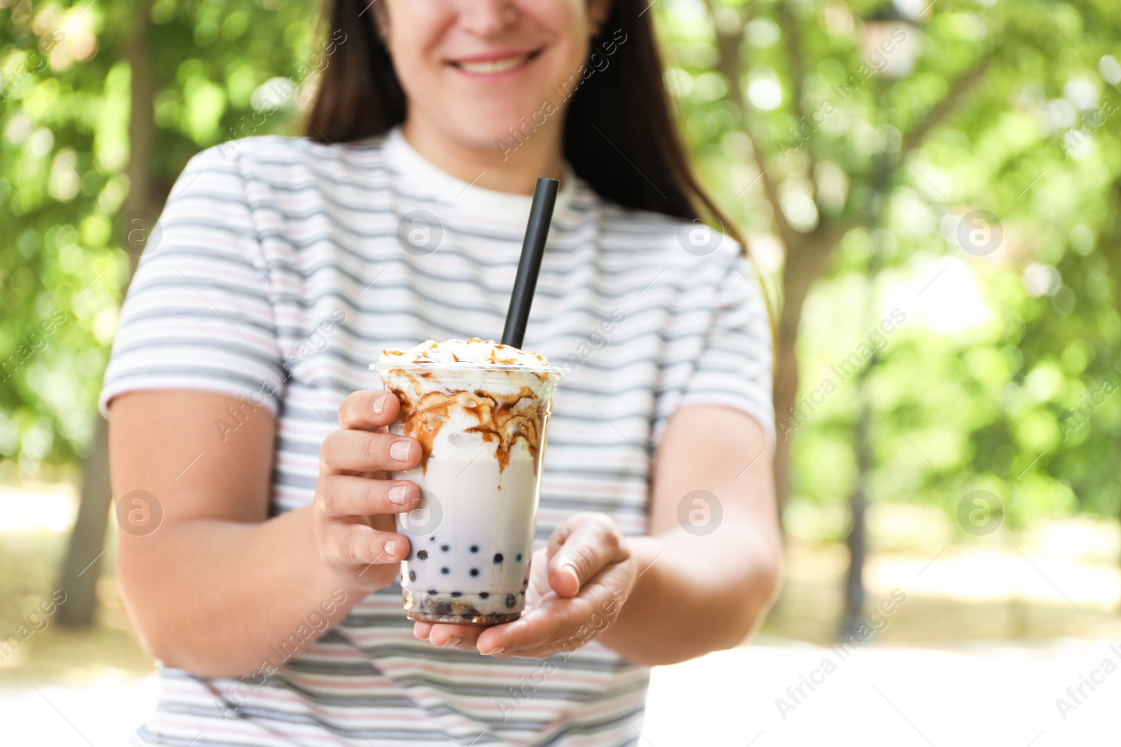 Woman with tasty milk bubble tea in plastic cup outdoors, closeup Photo of Woman with tasty milk bubble tea in plastic cup outdoors, closeup