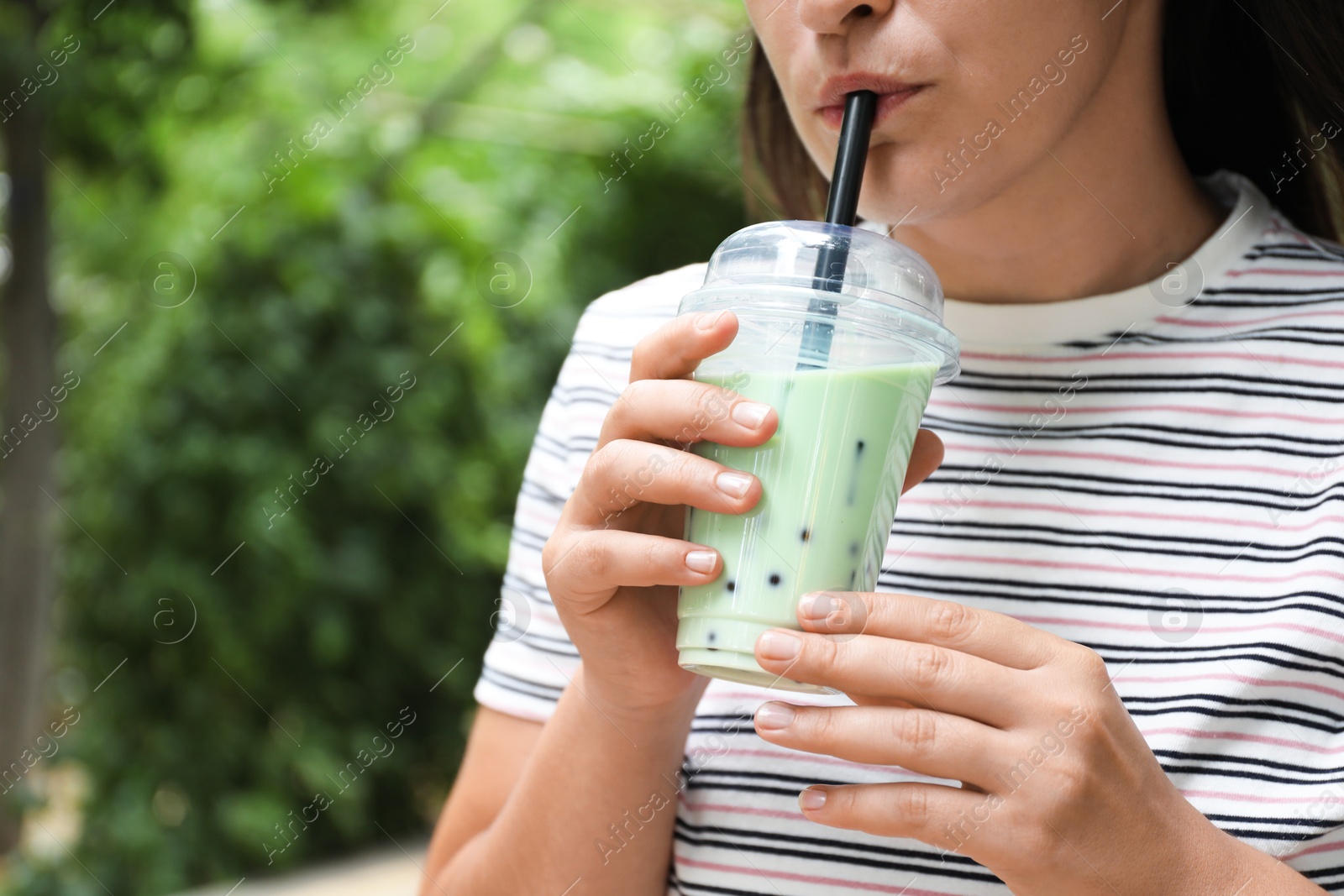 Woman drinking tasty milk bubble tea from plastic cup outdoors, closeup. Space for text Photo of Woman drinking tasty milk bubble tea from plastic cup outdoors, closeup. Space for text