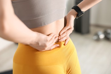 Photo of Sports injury. Young woman suffering from back pain in fitness studio, closeup