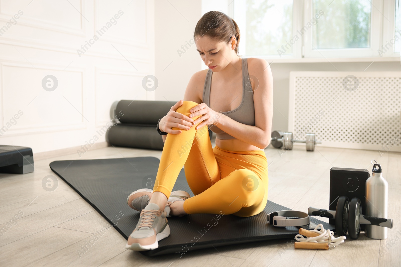 Sports injury. Young woman suffering from knee pain in fitness studio Photo of Sports injury. Young woman suffering from knee pain in fitness studio