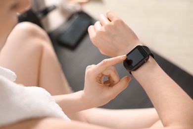 Photo of Woman checking fitness tracker during training indoors, closeup