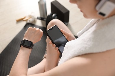 Photo of Woman checking fitness tracker during training indoors, closeup