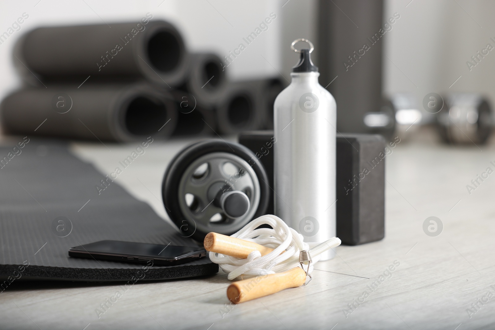 Photo of Phone and different fitness equipment on floor in gym, closeup