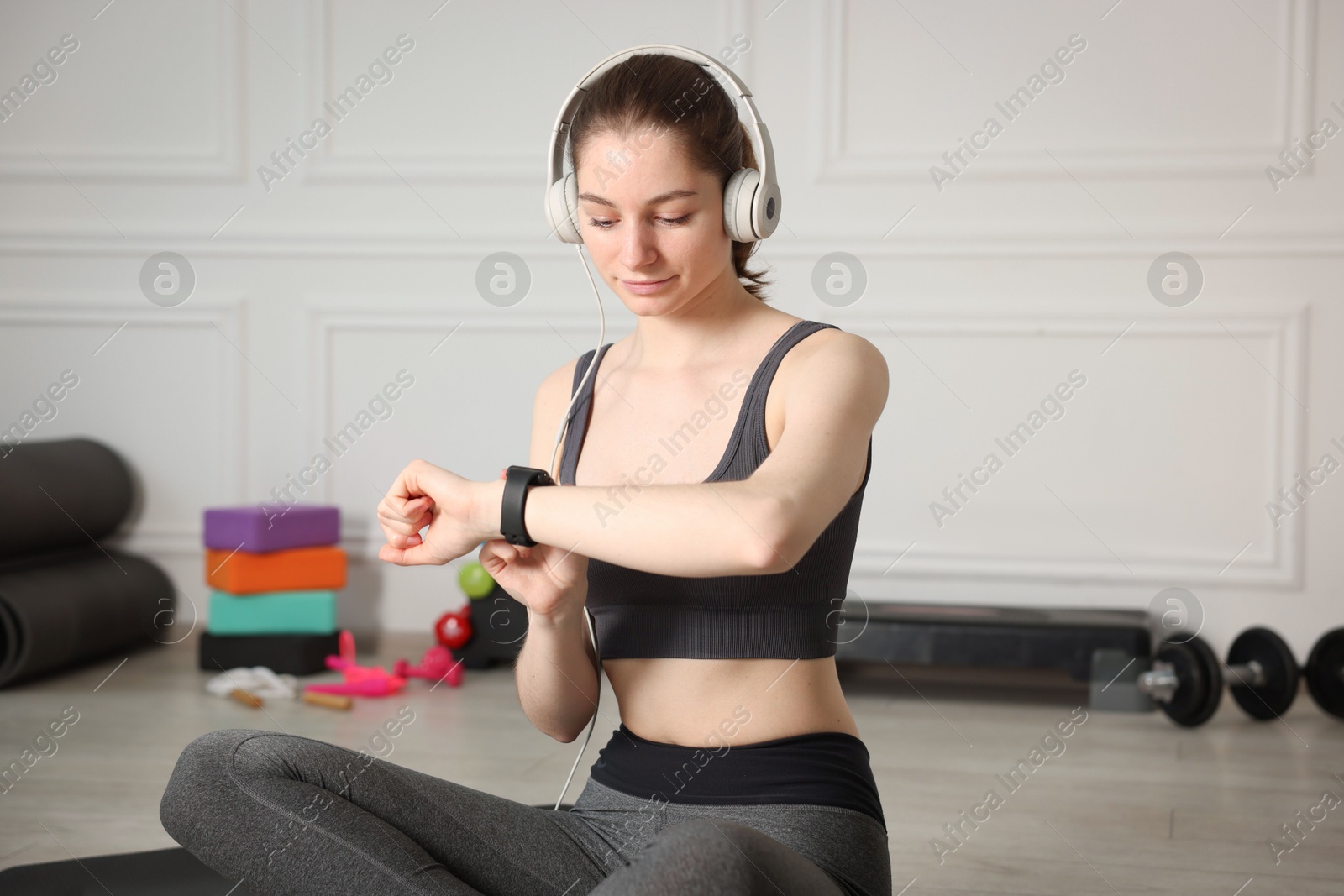 Woman checking fitness tracker during training indoors Photo of Woman checking fitness tracker during training indoors