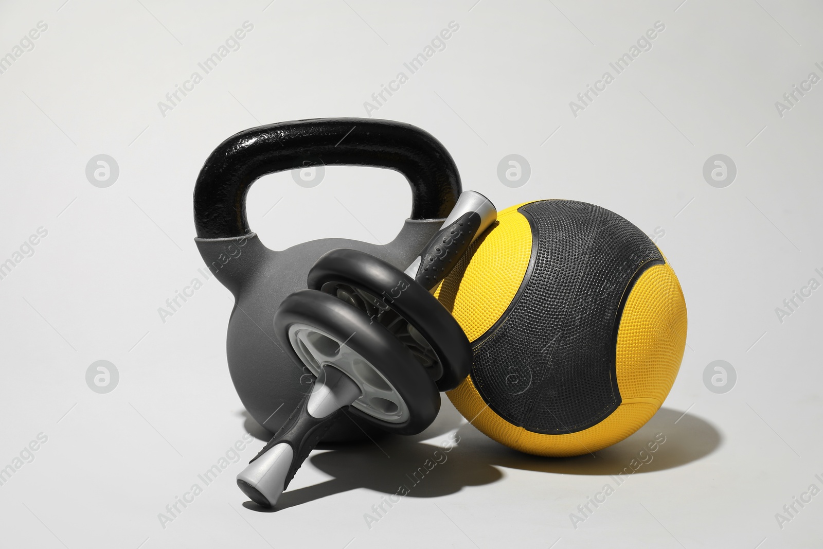 Photo of Medicine ball, ab wheel and kettlebell on light grey background