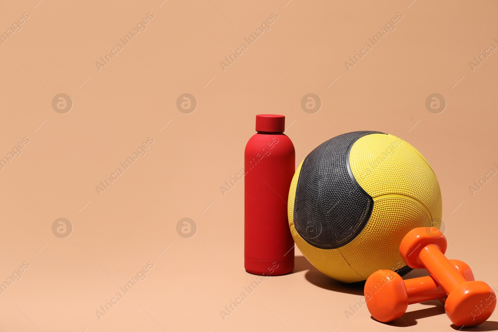Medicine ball, dumbbells and water bottle on beige background, space for text Photo of Medicine ball, dumbbells and water bottle on beige background, space for text