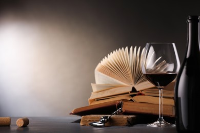 Photo of Red wine and books on dark textured table. Space for text
