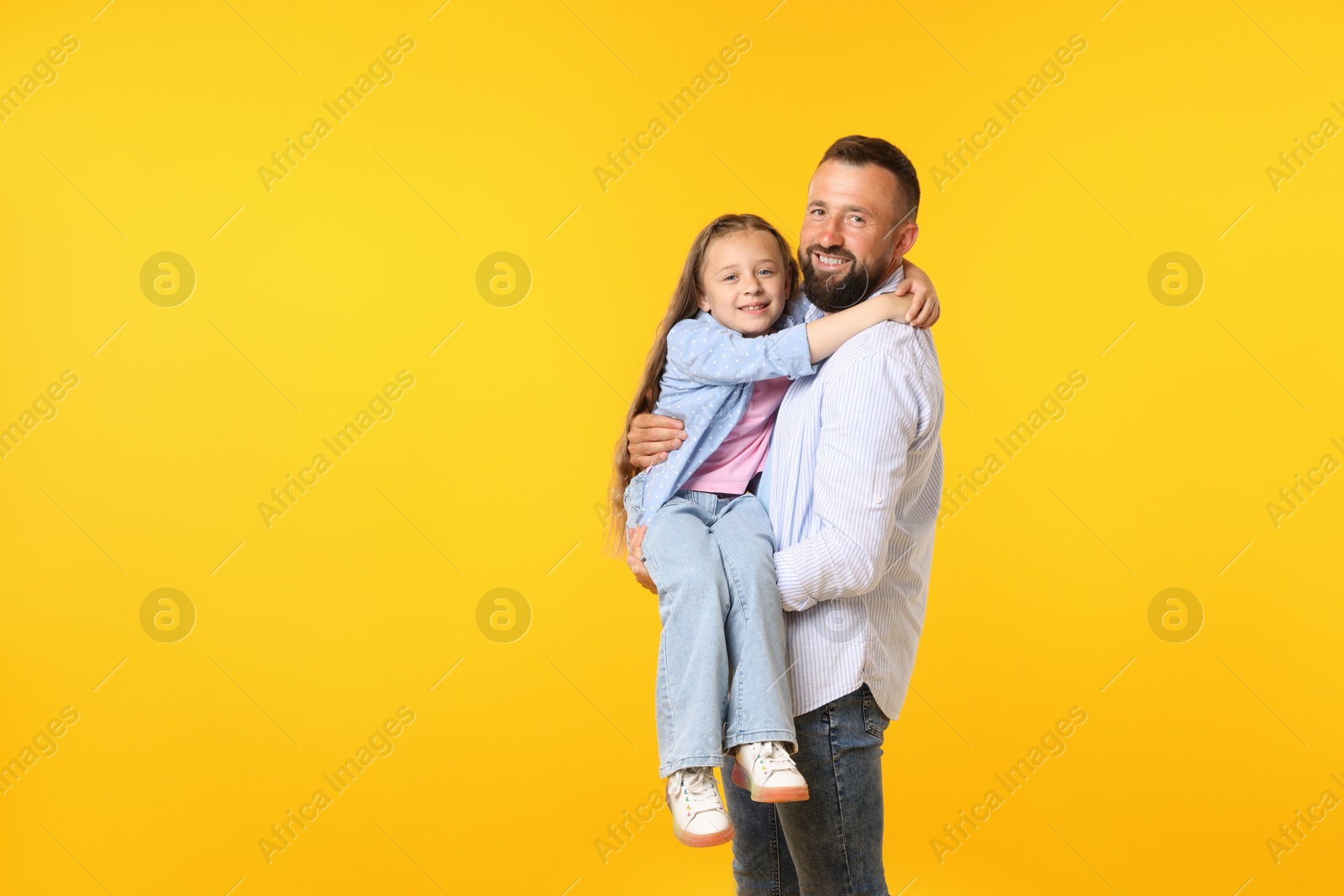 Family. Happy father and his daughter on yellow background. Space for text Photo of Family. Happy father and his daughter on yellow background. Space for text