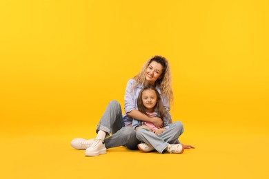 Photo of Family. Happy mother and her daughter on yellow background