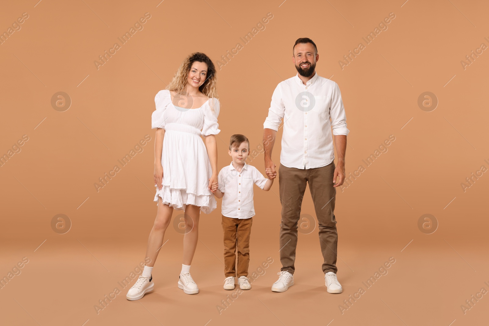 Family. Happy parents and their son on beige background Photo of Family. Happy parents and their son on beige background
