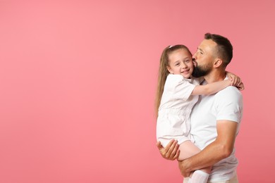 Photo of Family. Father kissing his happy daughter on pink background. Space for text