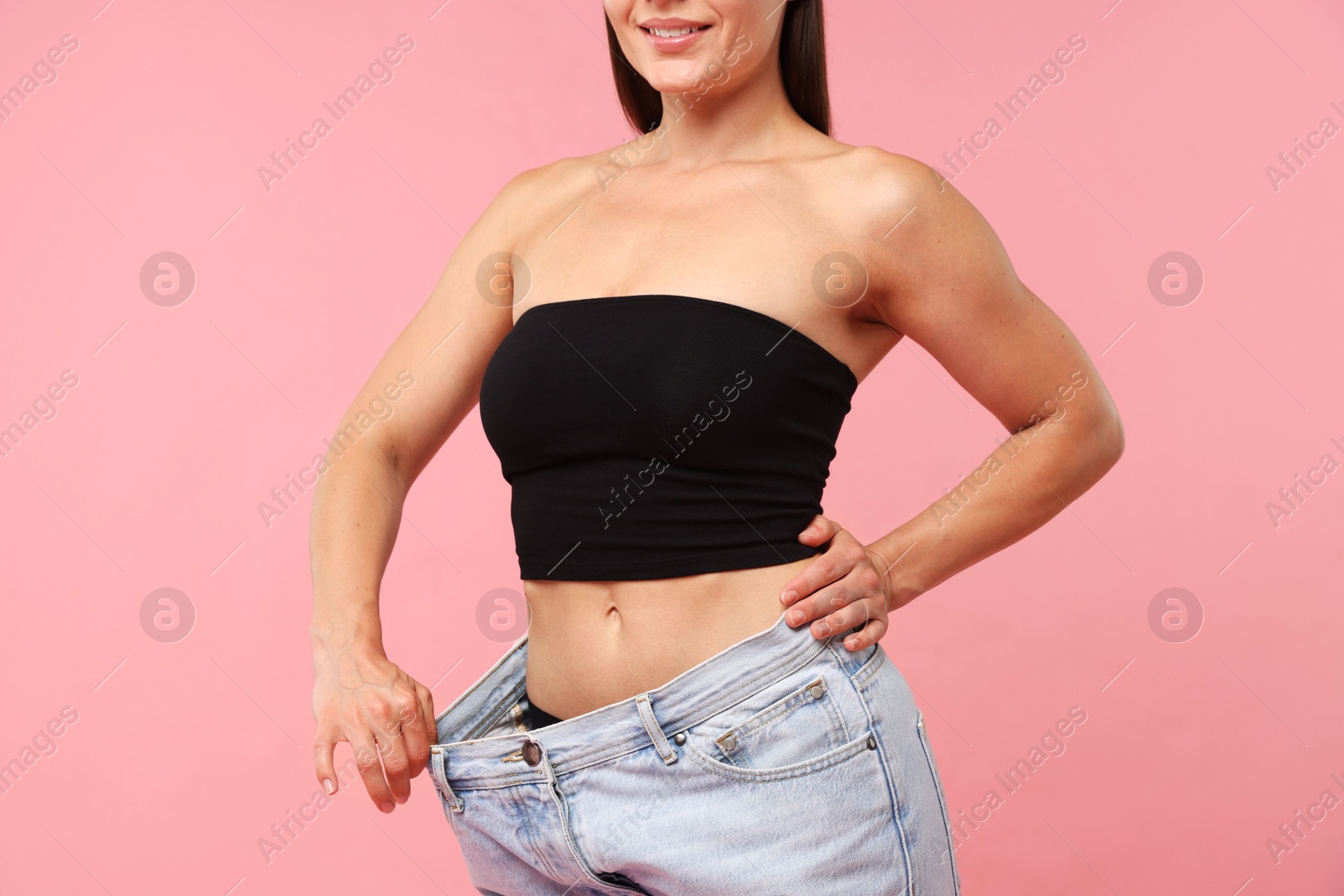 Fit woman wearing old jeans after weight loss on pink background, closeup Photo of Fit woman wearing old jeans after weight loss on pink background, closeup