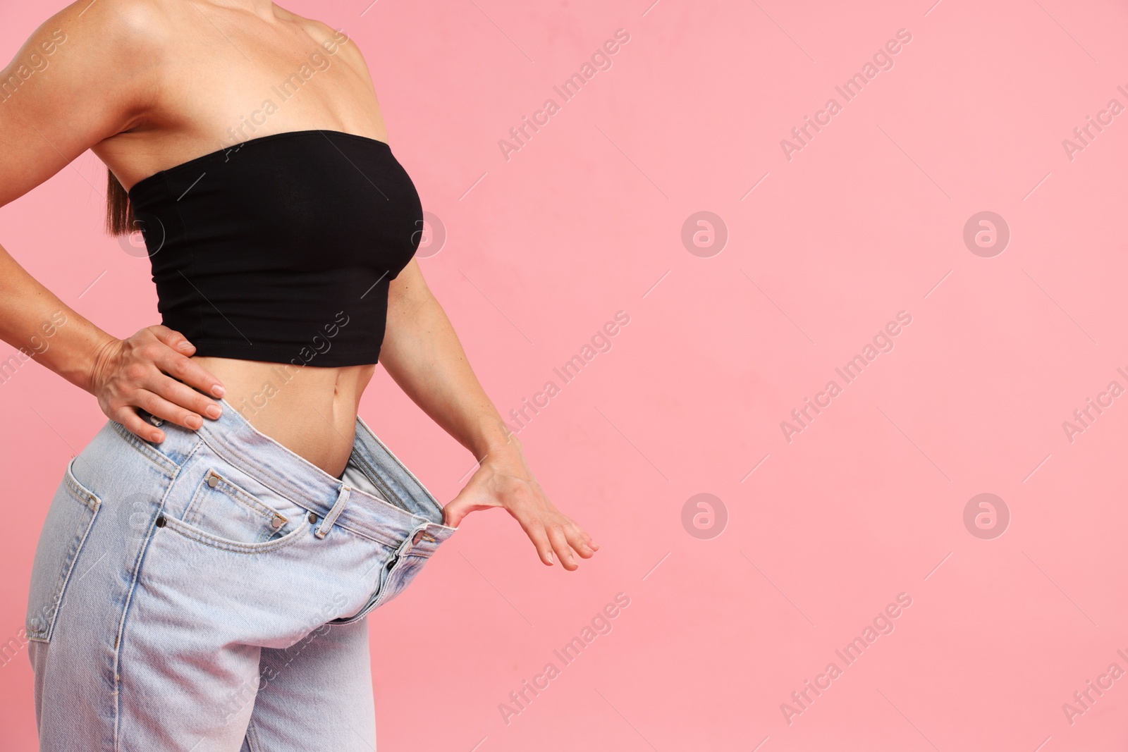 Fit woman wearing old jeans after weight loss on pink background, closeup. Space for text Photo of Fit woman wearing old jeans after weight loss on pink background, closeup. Space for text