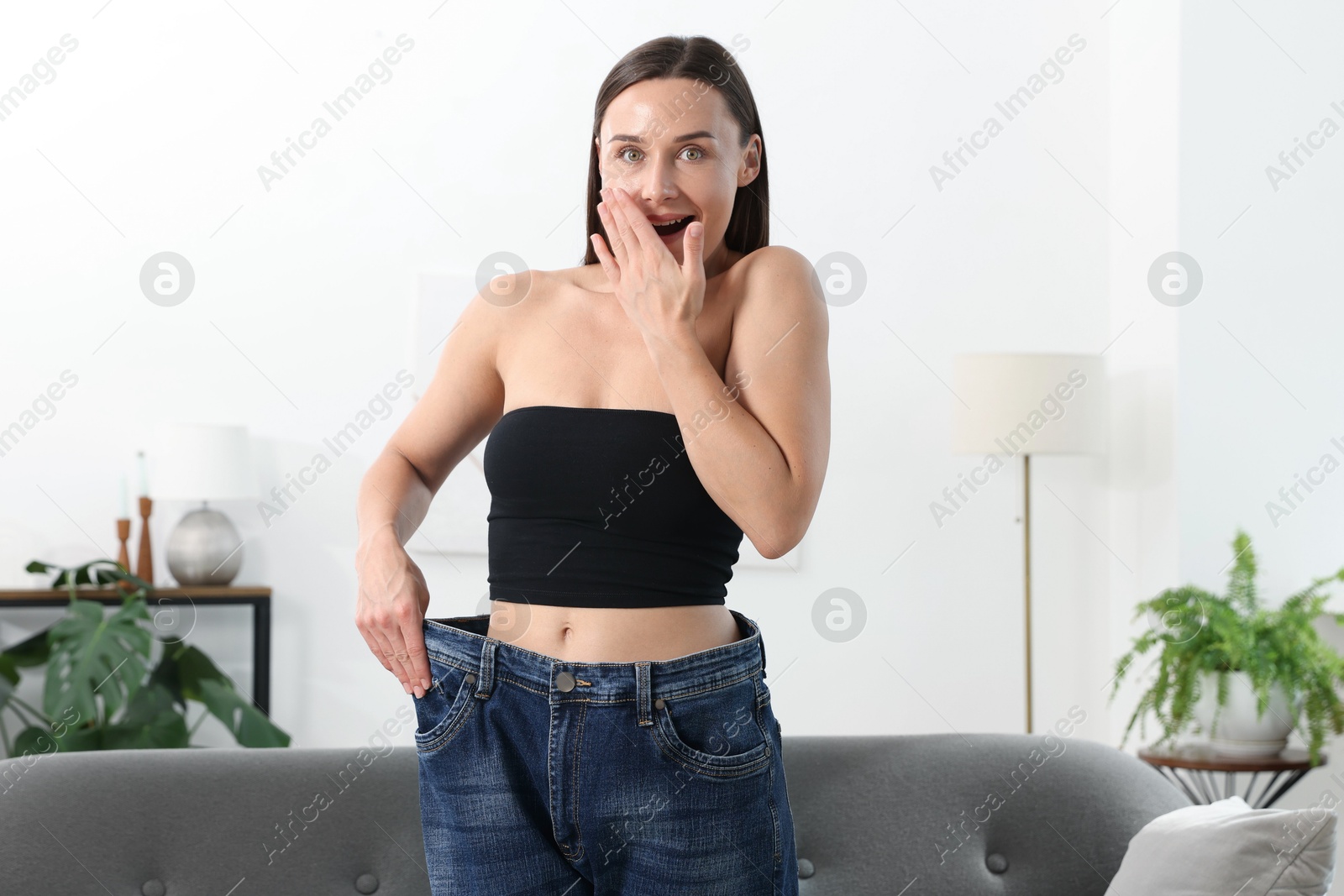 Excited woman wearing old jeans after weight loss at home Photo of Excited woman wearing old jeans after weight loss at home
