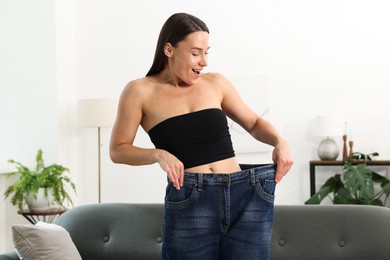Photo of Excited woman wearing old jeans after weight loss at home
