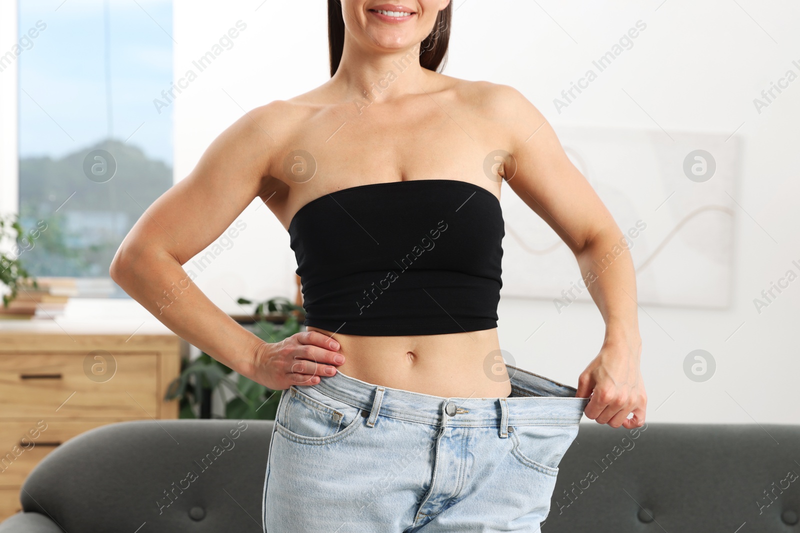 Fit woman wearing old jeans after weight loss at home, closeup Photo of Fit woman wearing old jeans after weight loss at home, closeup