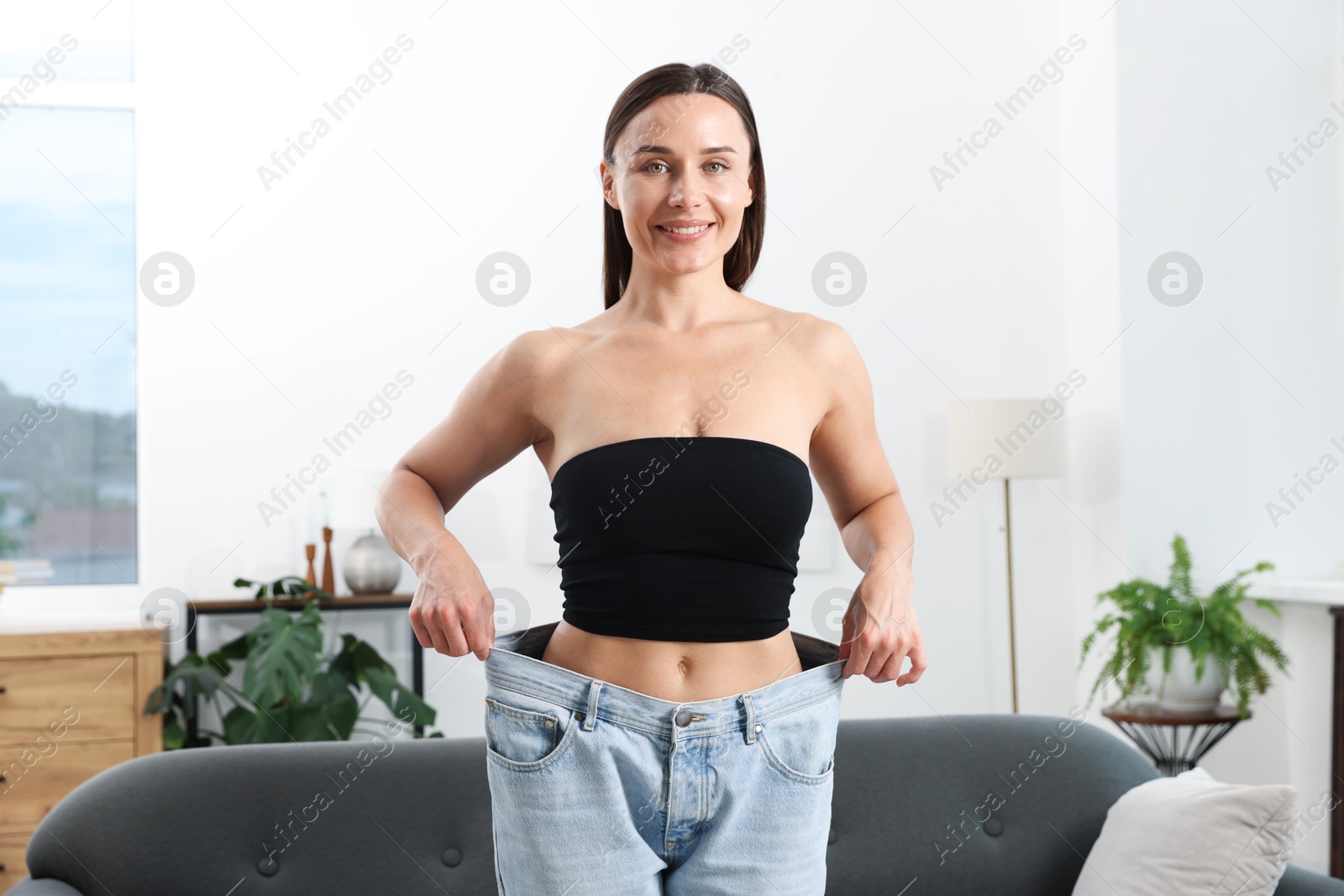 Fit woman wearing old jeans after weight loss at home Photo of Fit woman wearing old jeans after weight loss at home