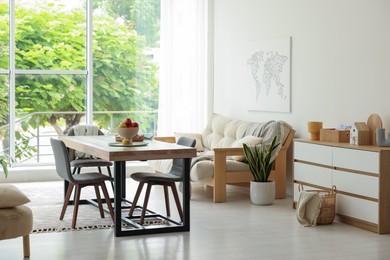 Photo of Wooden table, chairs, sofa and decor in dining room. Interior design