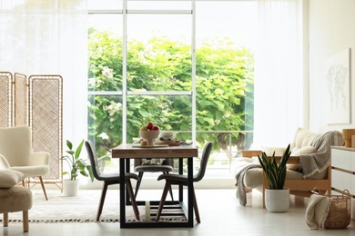 Photo of Wooden table, chairs, sofa and decor in dining room. Interior design