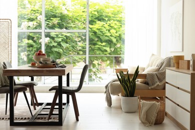 Photo of Wooden table, chairs, sofa and decor in dining room. Interior design