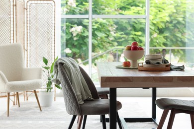 Photo of Wooden table, chairs, armchair and decor in dining room. Interior design