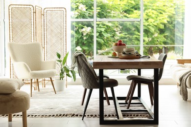 Photo of Wooden table, chairs, armchair and decor in dining room. Interior design