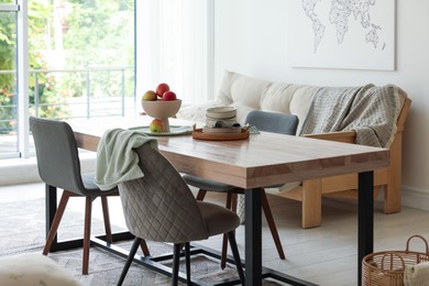 Photo of Wooden table, chairs, sofa and decor in dining room. Interior design