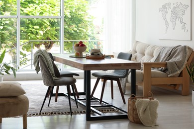 Photo of Wooden table, chairs, sofa and decor in dining room. Interior design