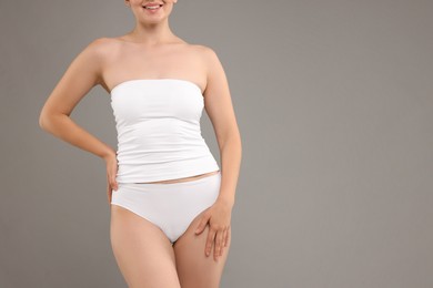 Photo of Woman in underwear on grey background, closeup. Space for text