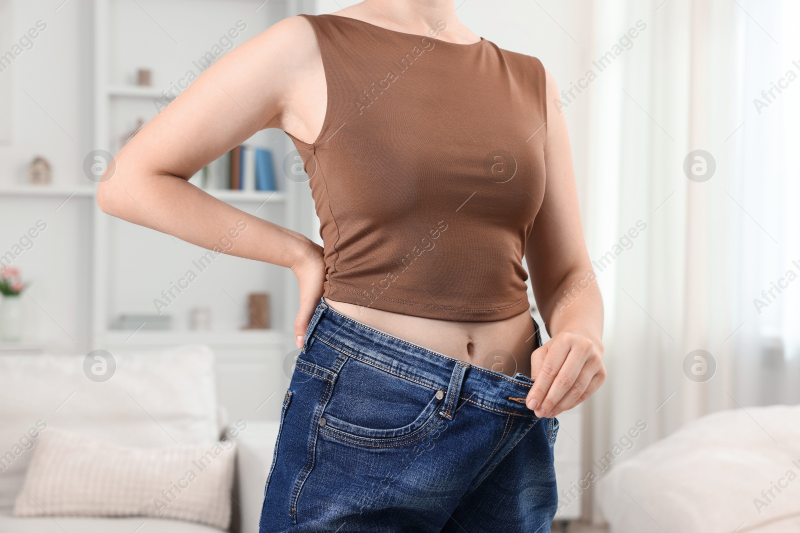 Woman wearing old jeans after weight loss indoors, closeup Photo of Woman wearing old jeans after weight loss indoors, closeup