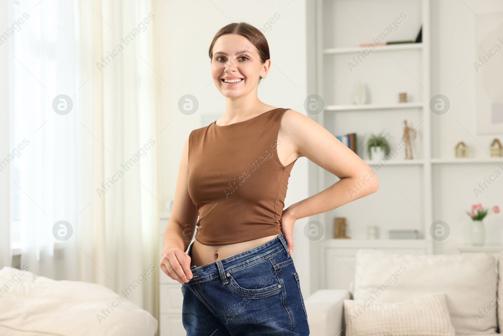 Photo of Beautiful woman wearing old jeans after weight loss indoors