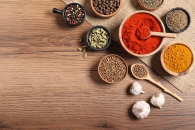 Photo of Different aromatic spices on wooden table, flat lay. Space for text