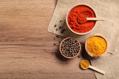 Photo of Different aromatic spices on wooden table, flat lay. Space for text