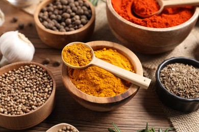 Photo of Different aromatic spices on wooden table, closeup